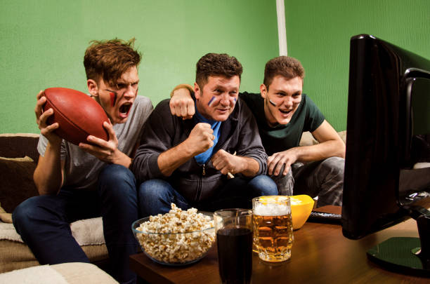 father and two sons watching american football match - american football football food snack imagens e fotografias de stock