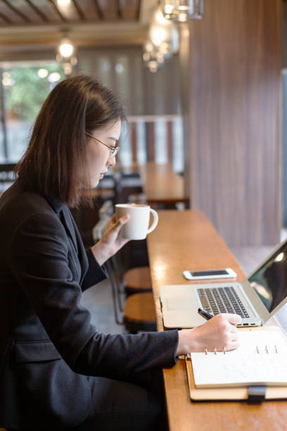 istock Young woman drinking coffee and working with laptop at cafe 881323778