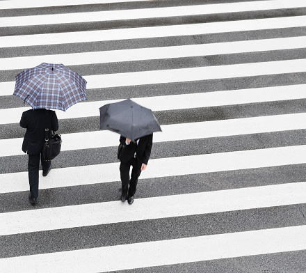 two businessmen at crosswalk on a rainy morning