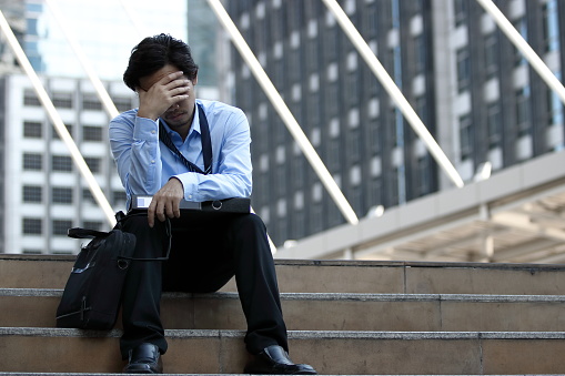 Frustrated stressed young Asian business man feeling tired and exhausted with job