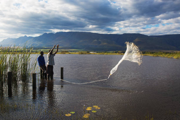 istock Men throw a fishing net into the water 881351356
