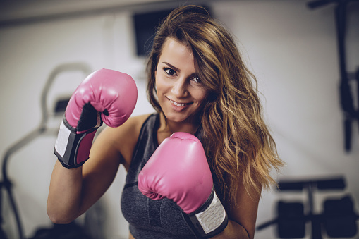 One woman, alone in gym, training with boxing gloves.