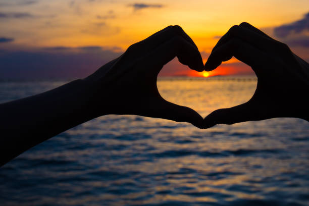 istock hands in heart shape at sunset on beach 881361694