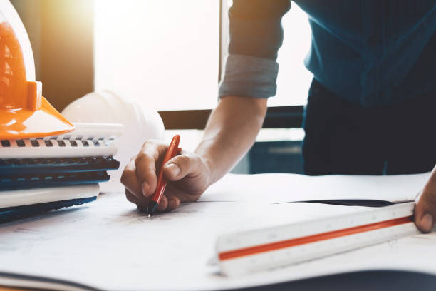 istock Image of engineer drawing a blue print design building or house, An engineer workplace with blueprints, pencil, protractor and safety helmet, Industry concept 881387706