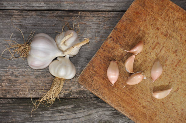 istock Garlic on old wooden board ready for cutting. 881415510