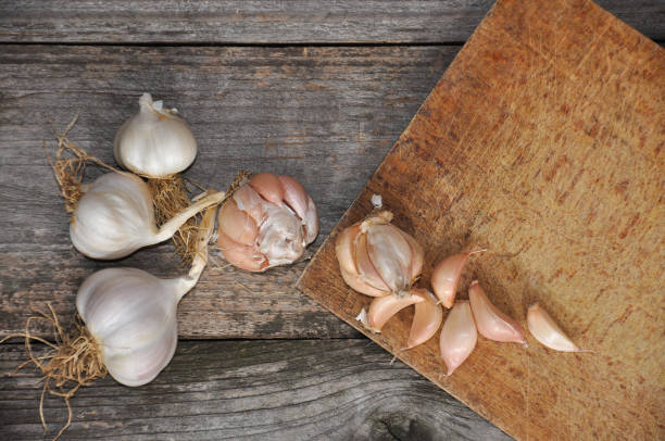 istock Garlic on old wooden board ready for cutting. 881415672