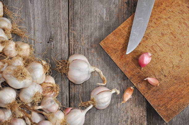 istock Garlic on old wooden board ready for cutting. 881418672