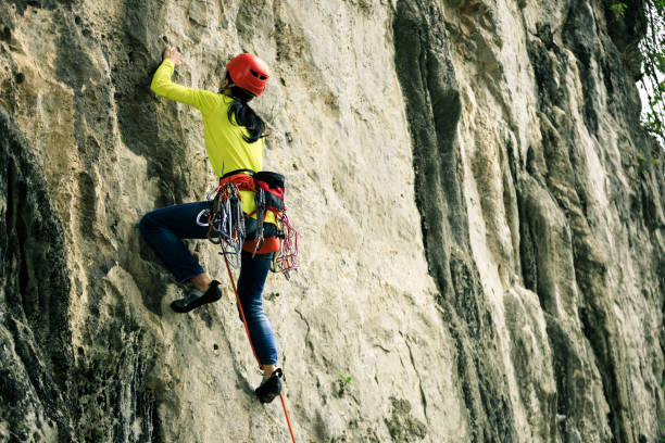 istock female rock climber climbing on mountain cliff 881421370