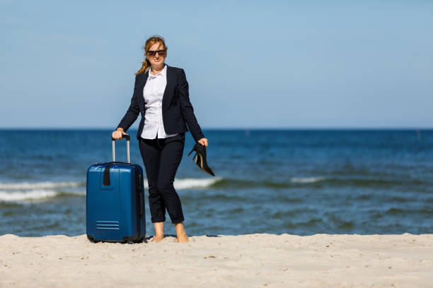 istock Businesswoman standing with suitcase at seaside 881424706