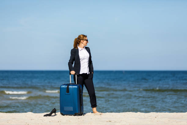 istock Businesswoman standing with suitcase at seaside 881424746