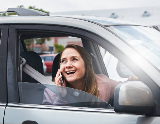 istock Woman driver looks through window smiling, talking on smartphone 881424966