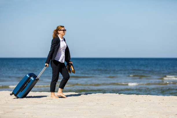 istock Businesswoman walking with suitcase at seaside 881424984
