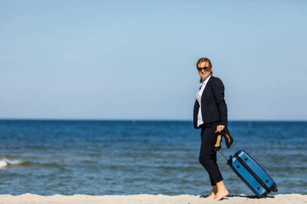 istock Businesswoman walking with suitcase at seaside 881425092