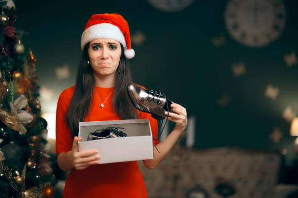 femme triste haïr recevant des chaussures plates comme cadeau de noël - holiday emotional stress christmas santa claus photos et images de collection