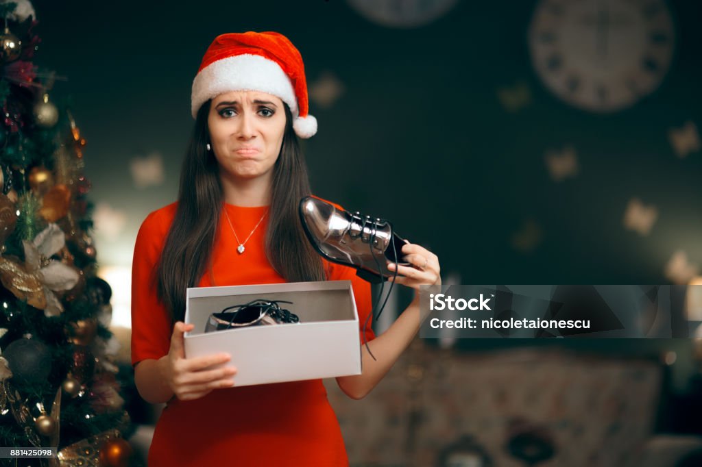 Sad Woman Hating Receiving Flat Shoes as Christmas Present Ungrateful girl with bad manners opening her Xmas present Gift Stock Photo