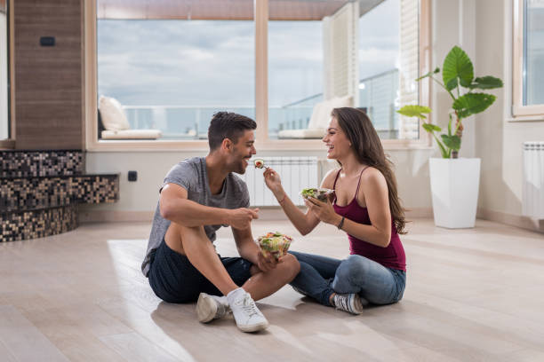 istock Young couple having fun while eating salad in their new home. 881442718