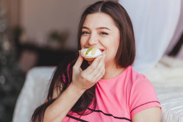 donna incinta che mangia torta sorridente. - human lips orange lipstick human mouth foto e immagini stock