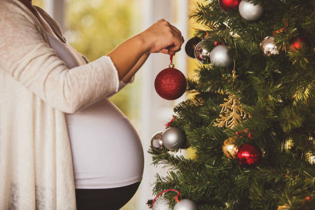 femme enceinte décorer le sapin de noël - christmas christmas ornament human hand decoration photos et images de collection