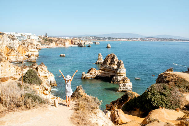 Woman on the rocky coastline in Lagos, Portugal Woman enjoying great view on the rocky coastline during the sunrise in Lagos on the south of Portugal lagos portugal stock pictures, royalty-free photos & images