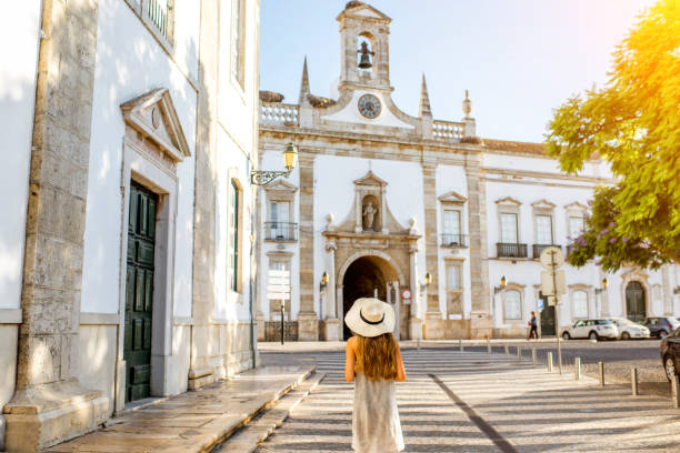 Woman traveling in Faro town on the south of Portugal Young woman tourist standing on the city gate background in Faro town on the south of Portugal algarve stock pictures, royalty-free photos & images