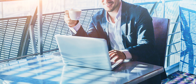 businessman working on computer, drinking coffee and smiling, abstract business banner background with place for text