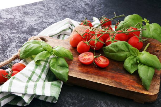 tomates cerises avec towl basilic et plat sur une planche à découper - towl photos et images de collection
