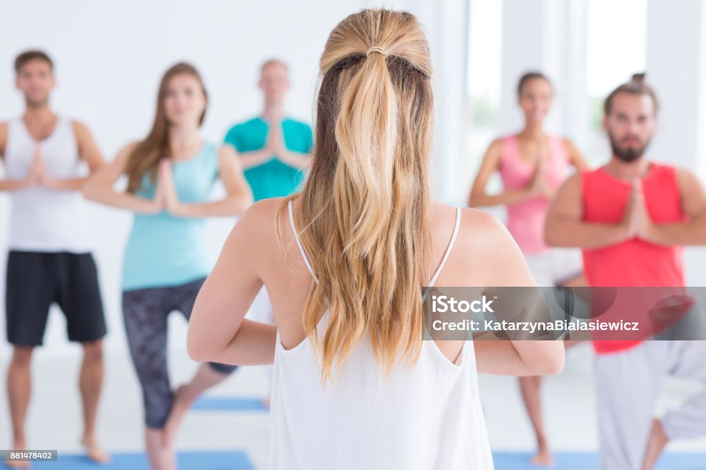Performing vrksasana pose Group of yogins performing vrksasana pose at yoga class in a gym Active Lifestyle Stock Photo