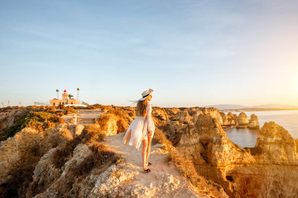 Woman traveling on the rocky coastline in Lagos, Portugal Woman enjoying great view on the rocky coastline during the sunrise in Lagos on the south of Portugal algarve holiday stock pictures, royalty-free photos & images