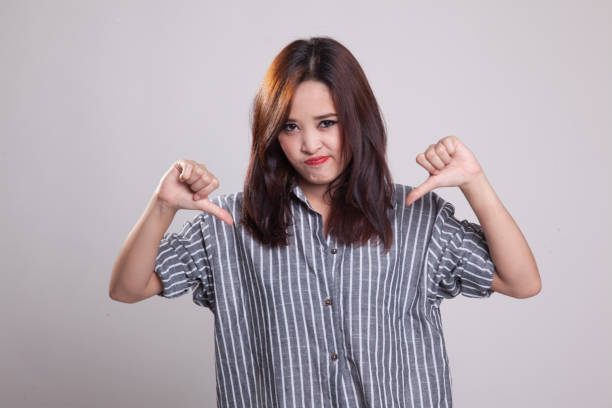 istock Unhappy Asian girl show thumbs down with both hands. 881483914