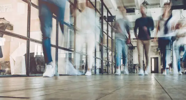 Multiracial young creative people in modern office. Successful hipster team in coworking. Businesspeople walking in the corridor of an business center. Motion blur.