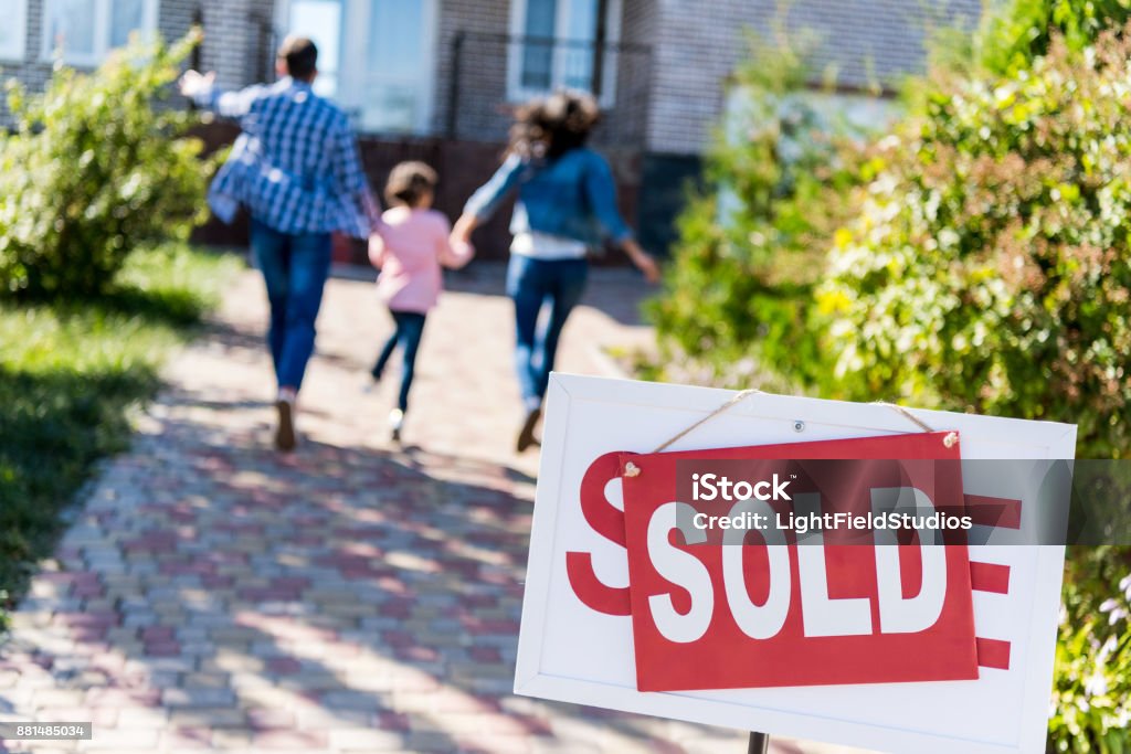 family running to new house family running to new house with sold signboard on foreground Selling Stock Photo