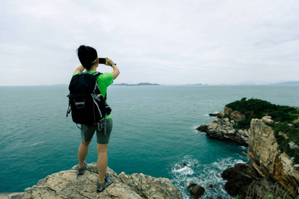 istock woman hiker using smartphone on seaside cliff 881488132