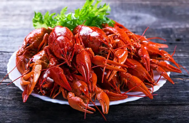 Big plate of tasty boiled crawfish closeup on wooden table, seafood dinner, nobody