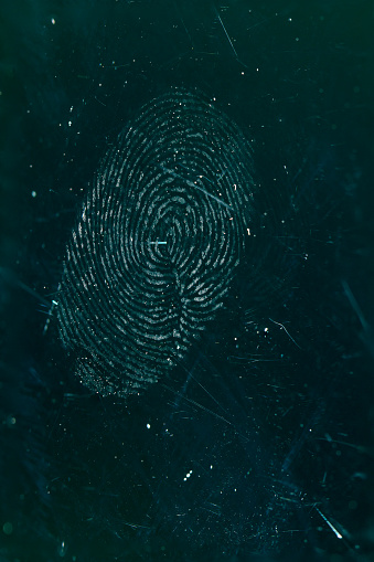 Fingerprint close-up. Identification symbol on old scratched glass.