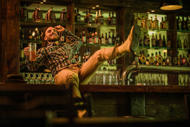 Playful man having fun in a pub while about to fall down from a bar counter.