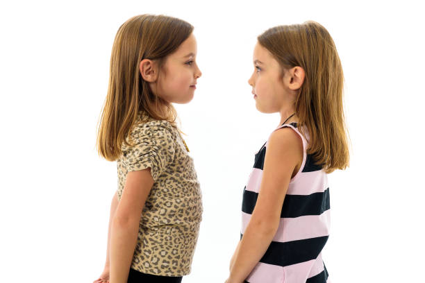 Identical twin girls are looking at each other and smiling.