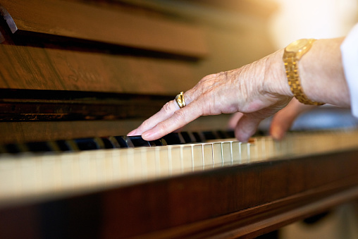 Shot of an unidentifiable senior woman playing the piano at home