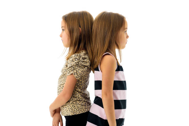istock Identical twin girls are turned back to back being sad. 881518598