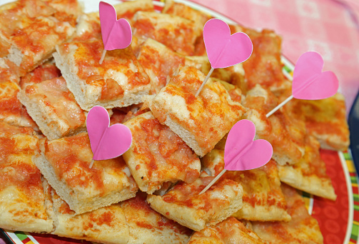 lots of pizza slices with heart-shaped flags at the little girl's party