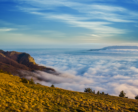 mountain slope, cloudy sky and dense fog