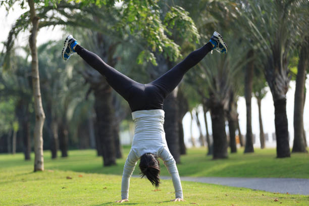 istock Young woman practice handstand on park meadow 881555420