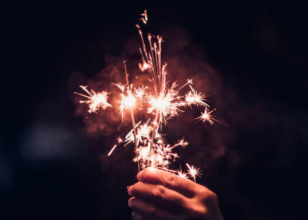 istock Hand holding burning Sparkler blast on a black background at night,holiday celebration event party,dark vintage tone. 881575838