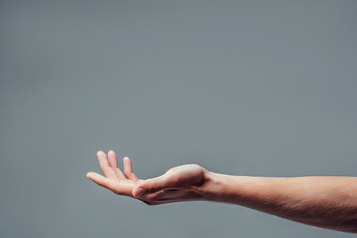 Man hand isolated on grey background. Holding something from below. Asking for help gesture.
