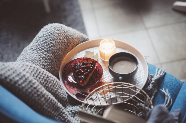 Cozy winter weekend at home. Morning with coffee or cocoa, books, warm knitted blanket and nordic style chair. Hygge concept.