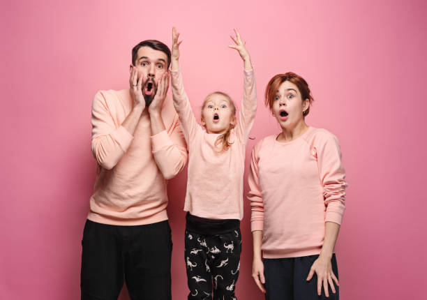 istock Surprised young family looking at camera on pink 881583280