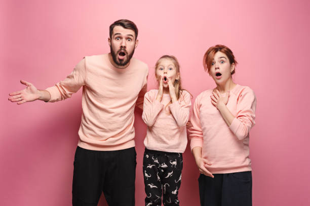 istock Surprised young family looking at camera on pink 881583626