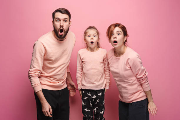 istock Surprised young family looking at camera on pink 881583722