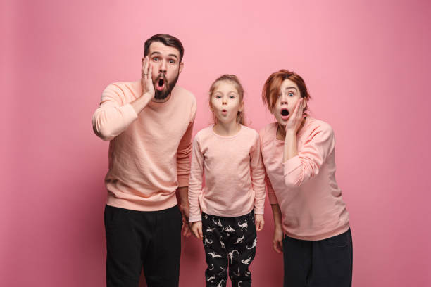 istock Surprised young family looking at camera on pink 881584096