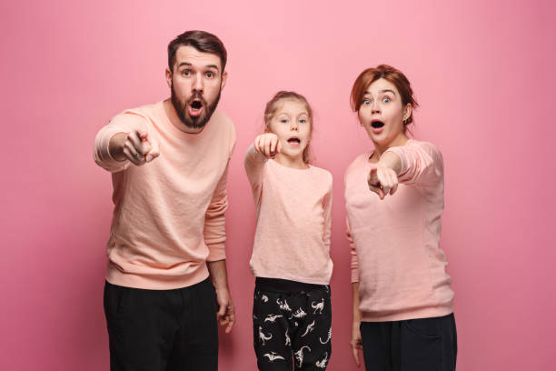 istock Surprised young family looking at camera on pink 881584302