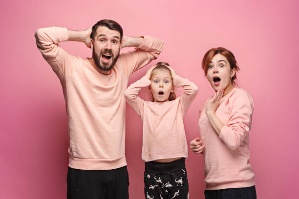 istock Surprised young family looking at camera on pink 881584490